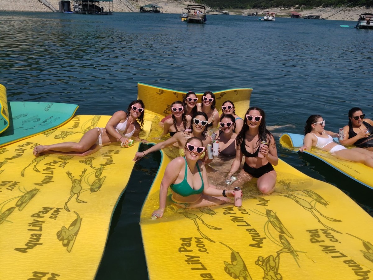 a bachelorette party having fun on a lily pad on Lake Travis